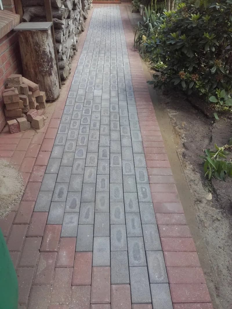 Gepflasterter Gartenweg aus Betonstein mit rotem Klinkerband – Wegebau Asmussen